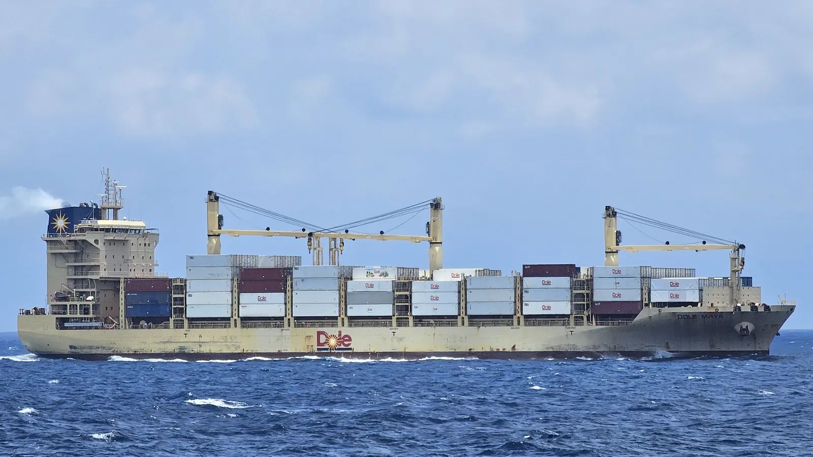 Loaded container ship at sea with a tugboat alongside, goods in transit covered by marine cargo insurance