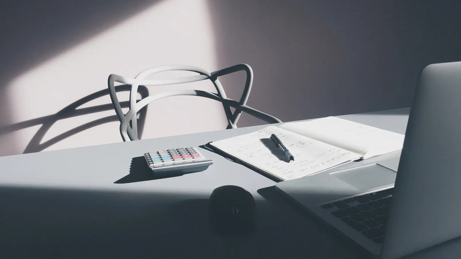 Desk with calculator, notebook, pen and laptop for checking trade invoices