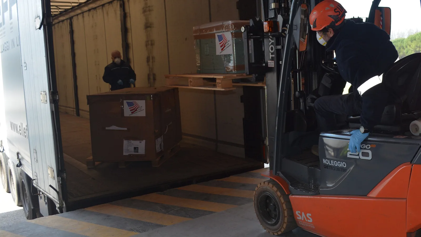 Forklift loading boxes into a truck at a warehouse dock, showing who loads the goods in EXW vs FCA