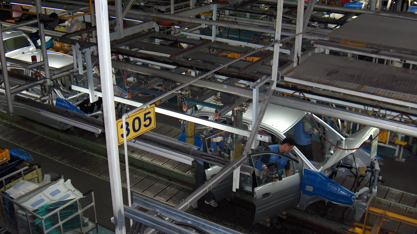 Overhead conveyor and assembly line inside a factory being assessed as a supplier
