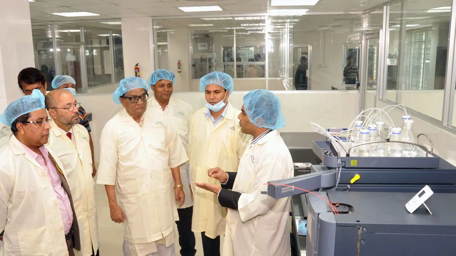 Visitors in protective clothing inspecting a production room, the kind of check done before goods ship
