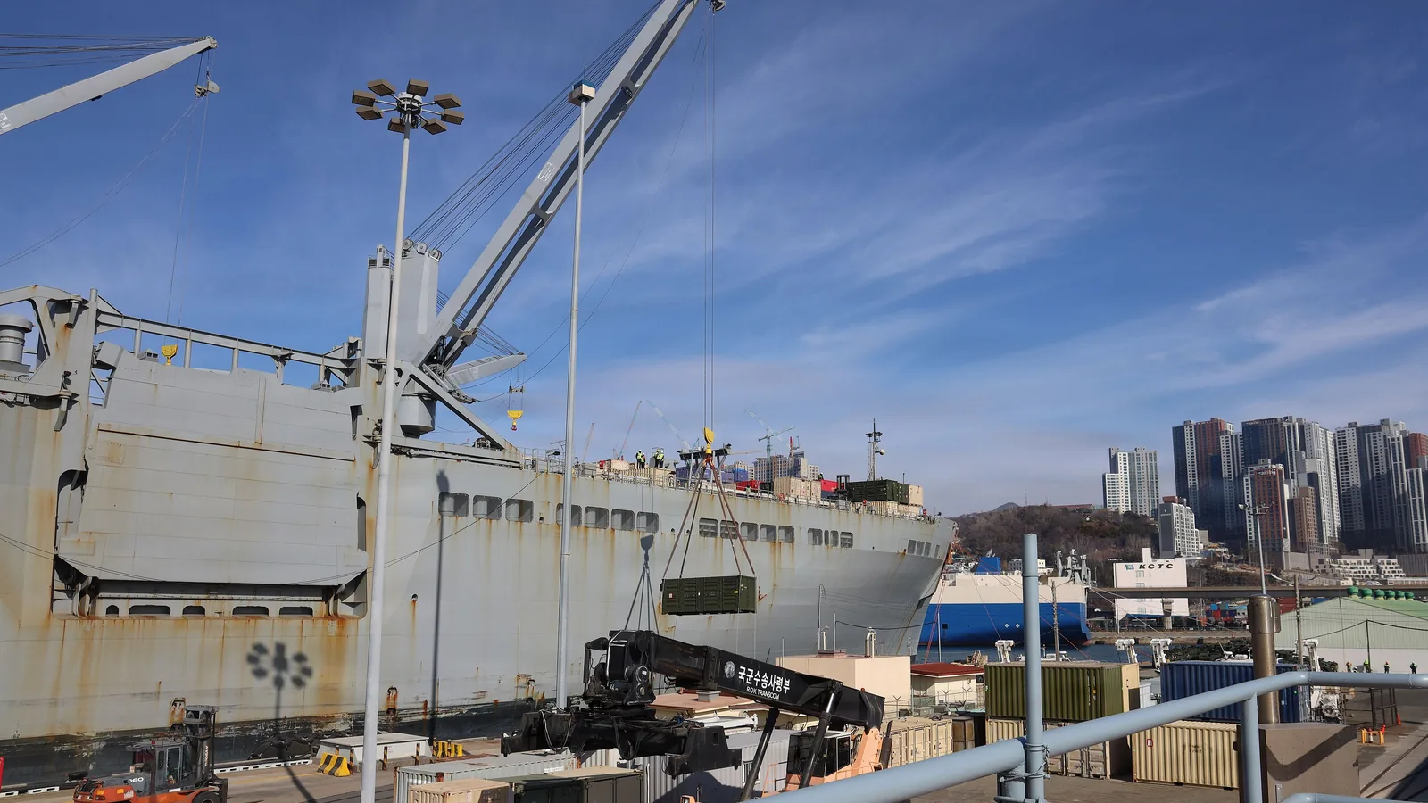 Crane lifting a container from a cargo vessel at a port quay, illustrating ocean freight surcharges charged at the terminal