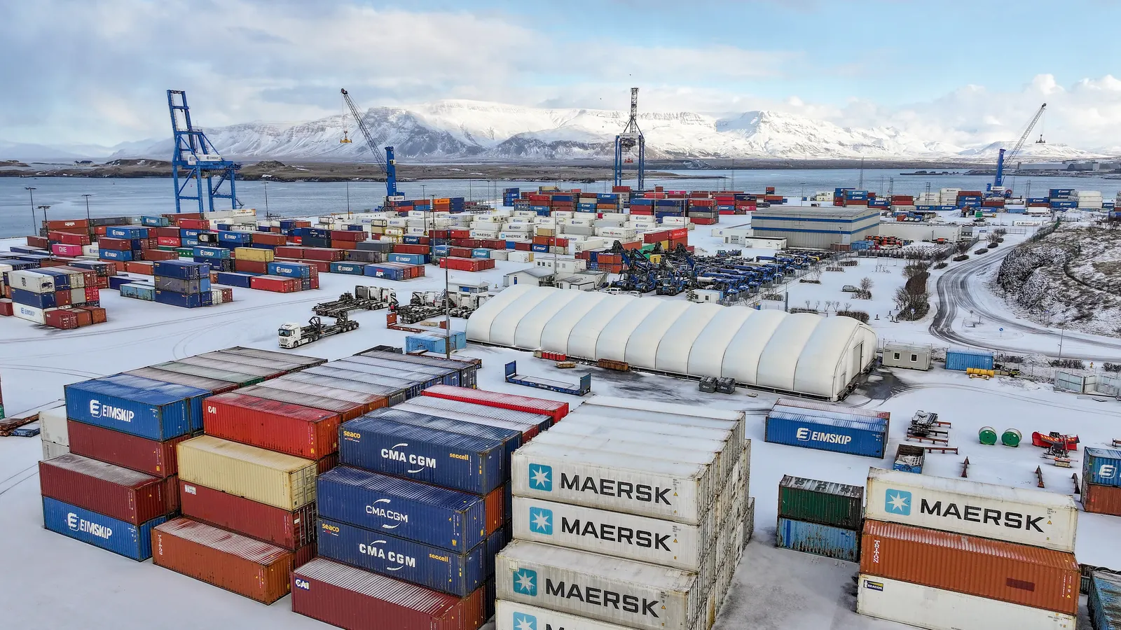 Stacked shipping containers at a port, the freight and handling costs behind landed cost
